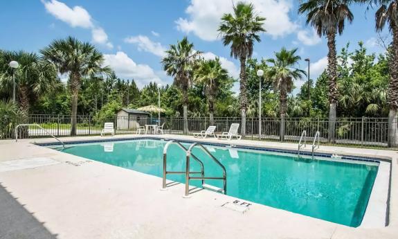 The outdoor pool is surrended by trees on two sides