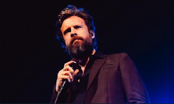 Singer/songwriter Father John Misty on stage with a microphone