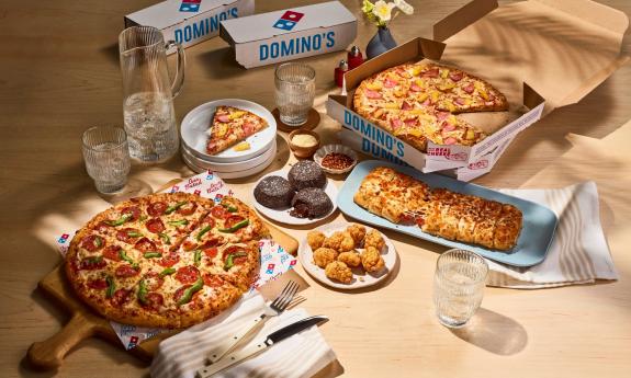 Pizza, sides, and dessert spread out on the table