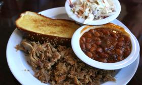 A plate of barbeque with Texas toast, baked beans, and coleslaw