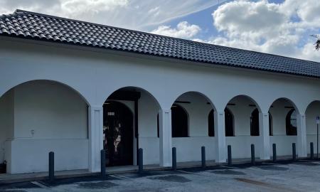 The exterior of a storefront with an arched walkway along the front