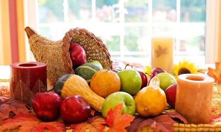 A cornucopia of fresh fall fruits and vegetables on a table in front of a window