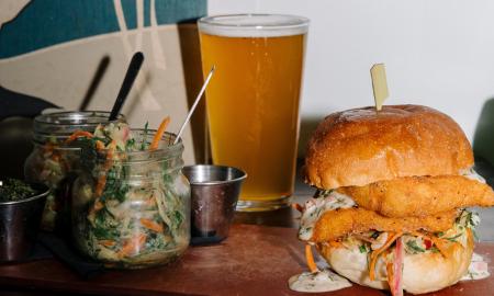 A sandwich stuffed with slaw and a pint of beer