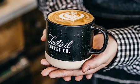 A hot latte served in a Foxtail branded mug