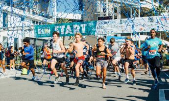 Runners at the starting line of McKenzie's Run beginning the race as blue confetti fills the air