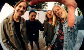 Bandmates from Switchfoot smile and pose in front of a fisheye lens. 