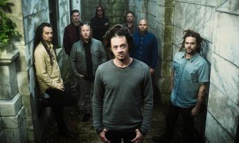 Bandmates from SOJA pose near marble walls. 