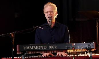 Randall Bramblett sings and plays the keyboard for fans in front of a black backdrop. 