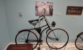 A vintage bicycle, made by Victor in a museum setting against a light blue wall