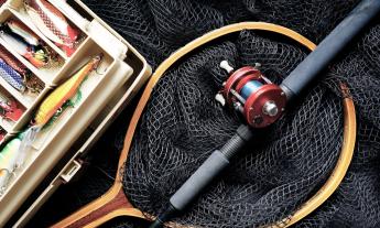 A fishing reel, net, and tackle box with various lures