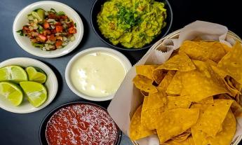 Chips with sides of salsa, queso, gaucamole, and pico de gallo