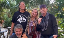 Carpetbaggers Band, one woman, three men, one guitar, standing in front of palmettos