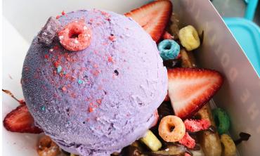The Dolly Llama purple colored ice cream surrounded by strawberries and fruit loops.