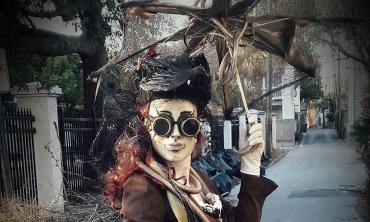 A woman with red hair, in full steampunk garb, holding a broken parasol